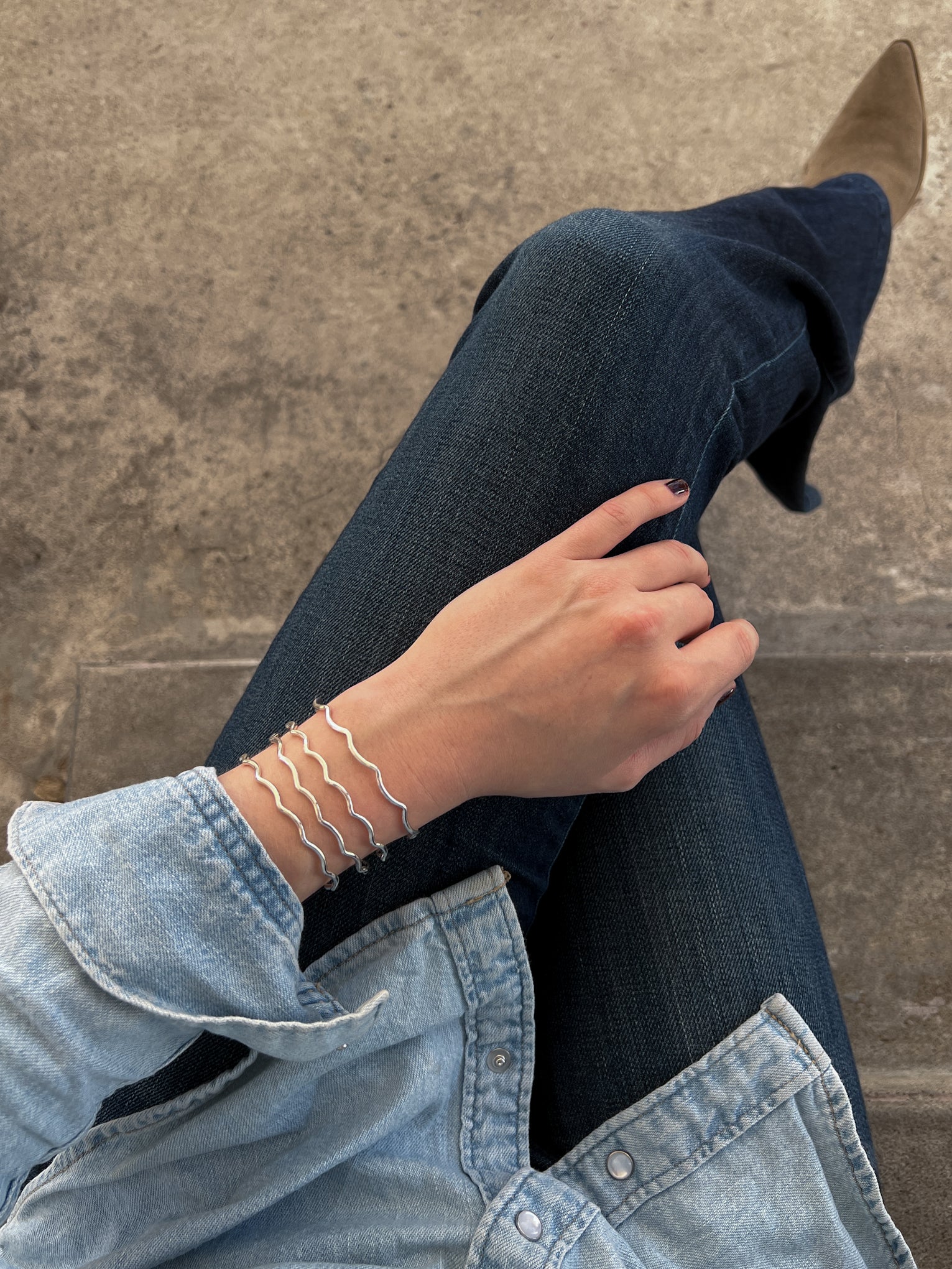 Lily Wujek wearing a stack of four Scallop Cuffs in Sterling Silver wearing blue jeans and a blue top