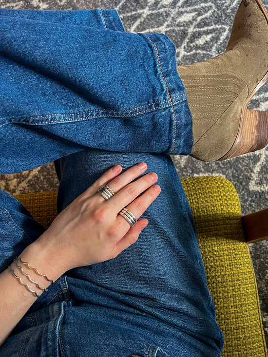 Lily Wujek's hand wearing the Bauble Ring and Scallop Cuff bracelets with her blue jeans and boots.