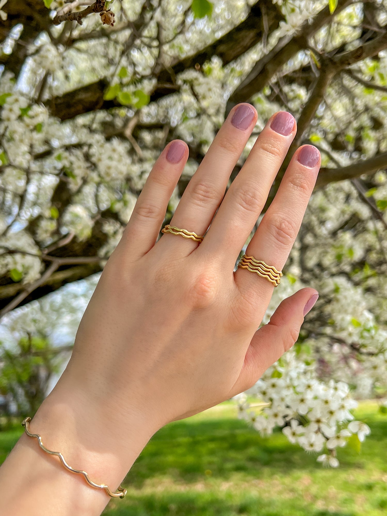 Jewelry designer Lily Wujek's hand wearing The Scallop Ring and The Scallop Cuff in 14k yellow gold