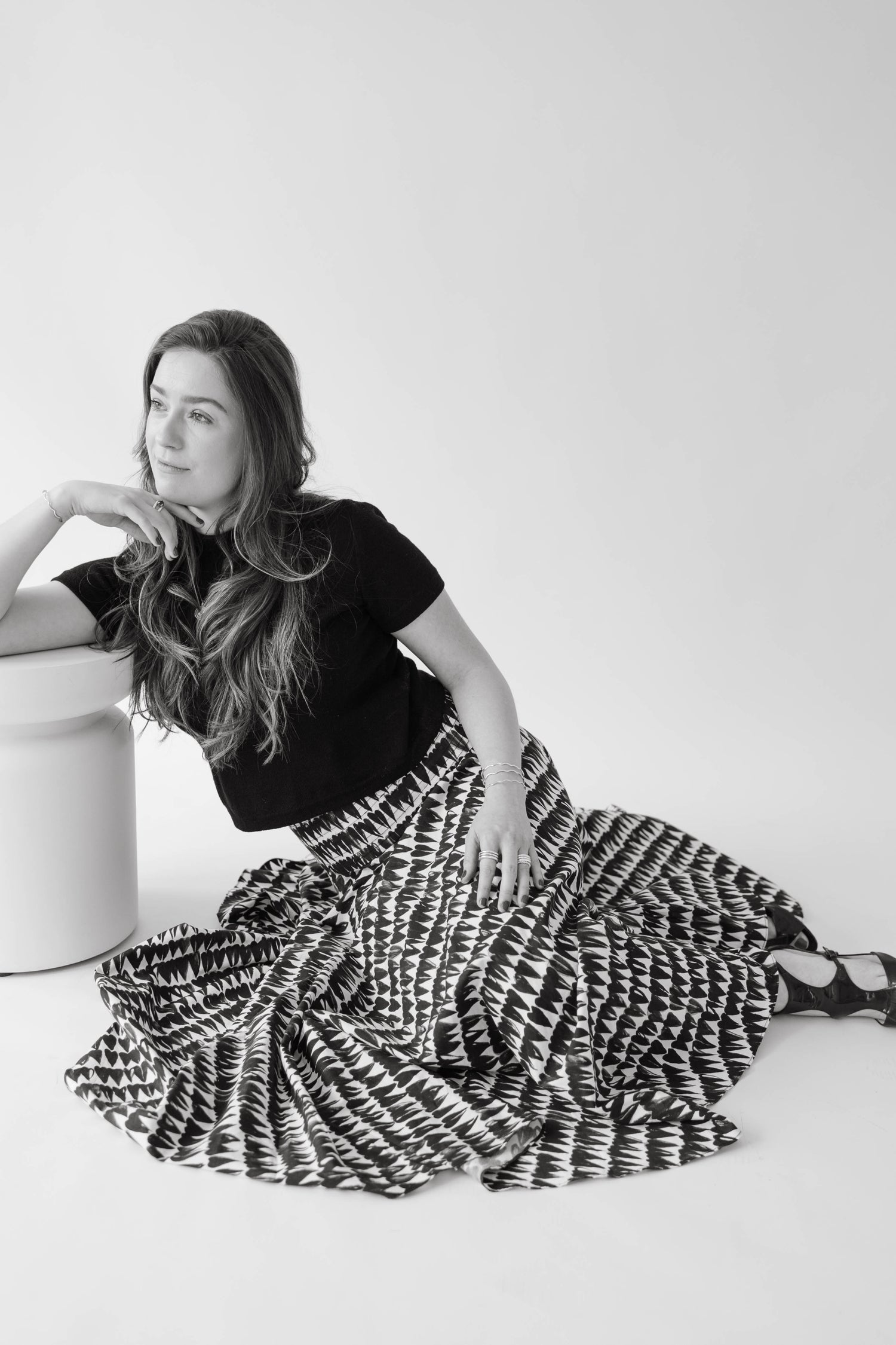 jewelry designer Lily Wujek sits on the floor in a wide black and white skirt